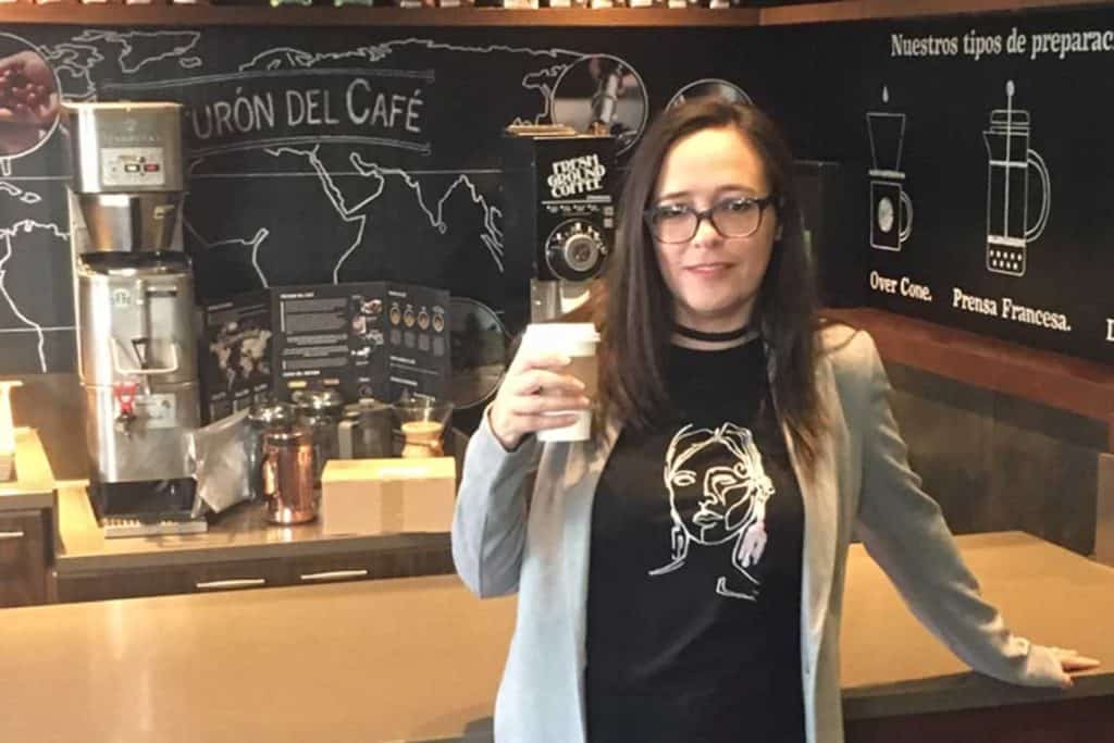 Foto del autor en frente de una barra de café sosteniendo una taza de café